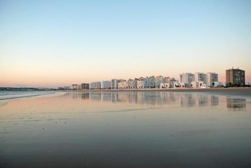 Una vista de una playa con edificios al fondo. en Apartamento La Rosa, en El Puerto de Santa María