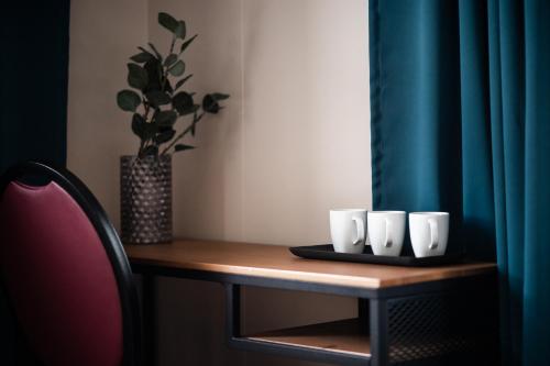 a table with three white cups and a potted plant at Holt Inn in Flateyri