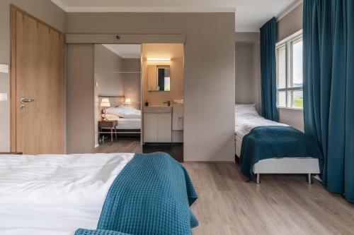 a bedroom with two beds with blue curtains at Holt Inn in Flateyri