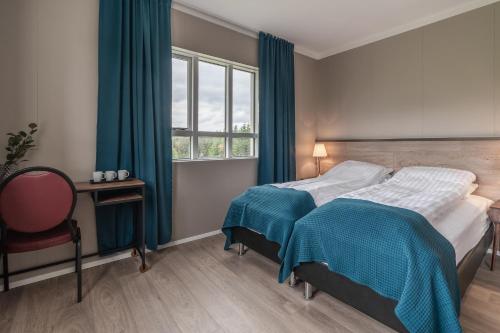a bedroom with a bed with blue curtains and a window at Holt Inn in Flateyri