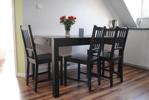 a black dining room table with two chairs and a vase of flowers at Apartament Nad Jeziorem Kaszuby in Gołubie