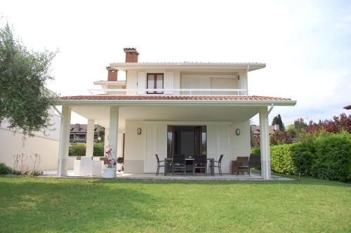 una casa blanca con sillas en el césped en Villa Sophora, en Moniga del Garda