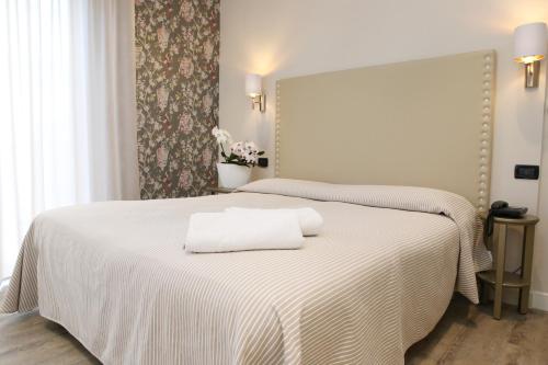 una camera da letto con un letto bianco con due asciugamani di Hotel Piccinelli a Rimini