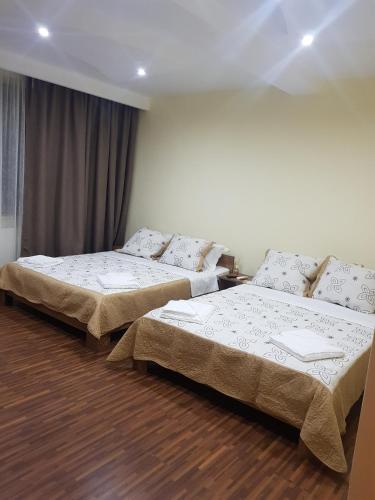 two beds in a room with wooden floors at Vila Nicol in Constanţa