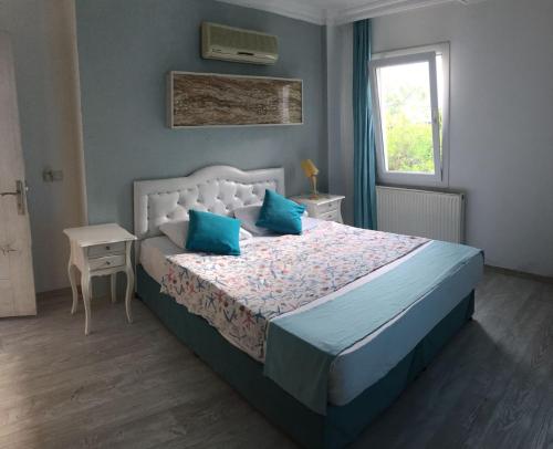 a bedroom with a bed with blue pillows and a window at Camlikosk Apart Hotel in Bodrum City