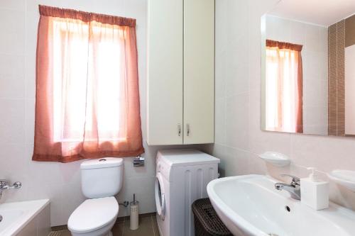 a white bathroom with a toilet and a sink at North Side Apartment 1 in Mġarr