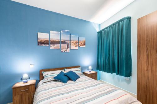 a blue bedroom with a bed with blue walls at North Side Apartment 1 in Mġarr