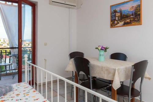 una mesa con sillas y un jarrón de flores. en Apartments Lončar, en Seget Vranjica