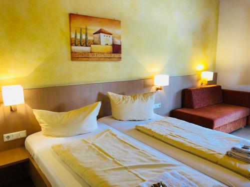 a hotel room with two beds and a chair at Hotel - Restaurant Hirschen - Werneths Landgasthof beim Europa- Park Rust in Rheinhausen