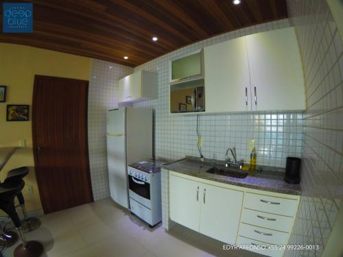 a small kitchen with white cabinets and a refrigerator at Residência Angra Deep Blue in Angra dos Reis
