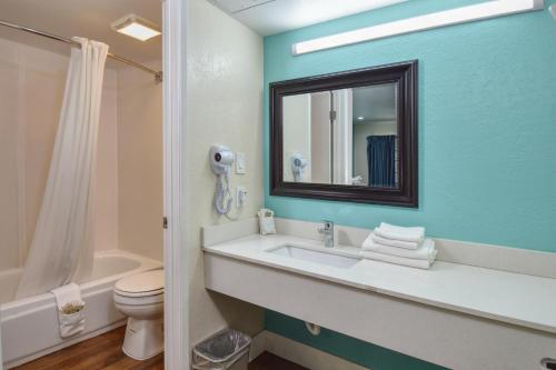 a bathroom with a sink and a toilet and a mirror at Vagabond Inn Buttonwillow North I-5 in Buttonwillow