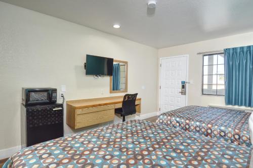 a bedroom with two beds and a desk and a television at Vagabond Inn Buttonwillow North I-5 in Buttonwillow