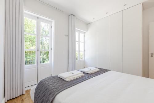 a white bedroom with a bed with two towels on it at Ana`s Houses in Guimarães