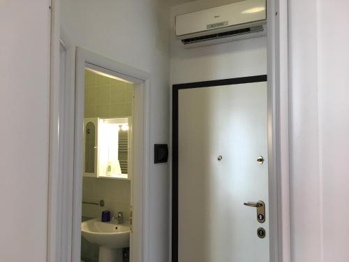 a bathroom with a door leading to a sink at Bianco&Nero 61 Apartament in Margherita di Savoia