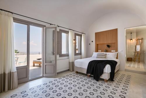 a bedroom with a bed and sliding glass doors at White & Co. La Torre Suites in Pyrgos