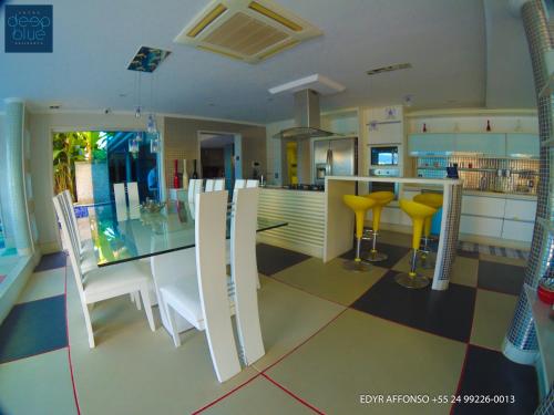 a kitchen with a glass table and yellow chairs at Residência Angra Deep Blue in Angra dos Reis
