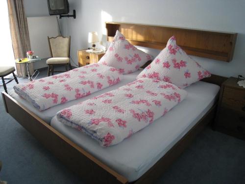 a bed with pink and white pillows on it at Landhaus Mast in Baiersbronn