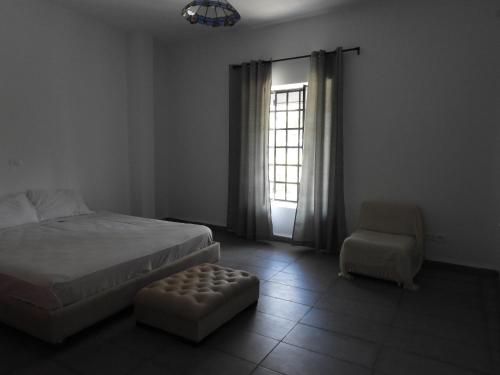 Appartement quartier Dar Sebastian, Hammamet في الحمامات: غرفة نوم بسرير وكرسي ونافذة