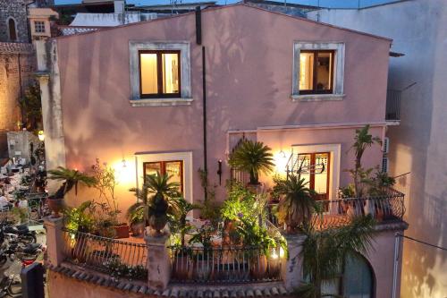 a pink house with palm trees on a balcony at Al Duomo Rooms & Flats in Taormina
