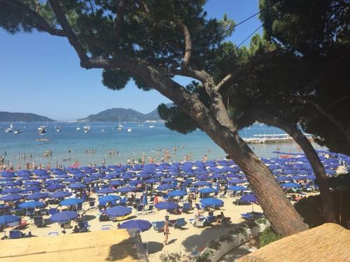 a beach filled with lots of people and blue umbrellas at Affittacamere La Baia Di Lerici in Lerici