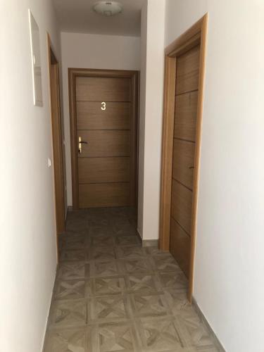 a hallway with two wooden doors and a tile floor at Apartment & Rooms Thomas in Korenica