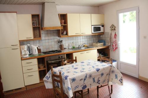 une cuisine avec une table et des placards blancs dans l'établissement Maison Ile de Ré - Bois Plage en Ré, au Bois-Plage-en-Ré
