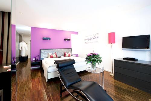 a hotel room with a bed and a chair and a tv at Alpenlove - Adult SPA Hotel in Seefeld in Tirol