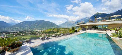 a house with a swimming pool with mountains in the background at Boutique Hotel Eschenlohe in Schenna