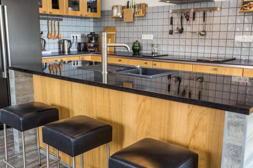 a kitchen with a sink and two stools at VIVAZA Villa Szigliget in Szigliget