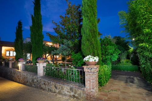 a fence with potted plants and trees at night at Villa Marín Toledo in Las Nieves