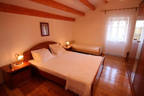 a bedroom with a large white bed and a window at Holiday Home Krista in Miholašćica