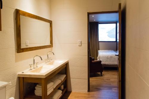 a bathroom with a sink and a mirror and a bed at Villa Montaña in Las Lenas
