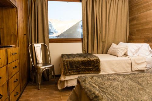 a bedroom with a bed and a chair and a window at Villa Montaña in Las Lenas