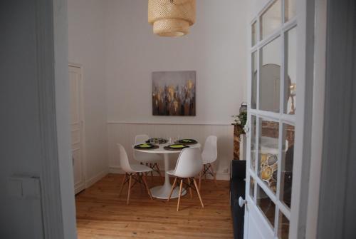 une salle à manger avec une table et des chaises blanches dans l'établissement L'authentique - Coeur de ville, à Toulouse