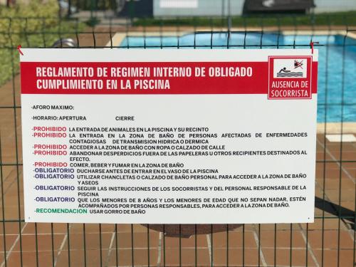 a sign on the fence of a swimming pool at Casa de Las Flores - Apartamento con jardín privado frente a la Playa de Comillas in Comillas