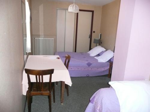 Cette chambre comprend deux lits, une table et des chaises. dans l'établissement Hôtel Restaurant du Pont Vieux, à Camarès