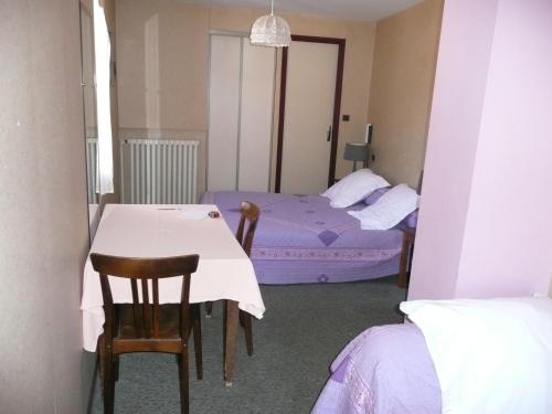 a room with two beds and a table and chairs at Hôtel Restaurant du Pont Vieux in Camarès