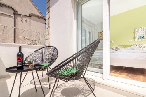 a chair and a table on a balcony with a bed at 4 Elements Old Town Views Rooms in Trogir