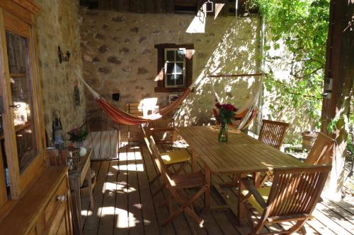 une table en bois avec des chaises et un hamac sur la terrasse. dans l'établissement Les Hortensias, à Riquewihr