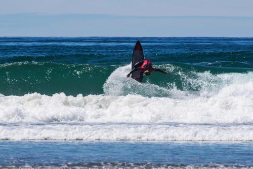 a person riding a wave on a surfboard in the ocean at Tico Adventure Lodge in Sámara