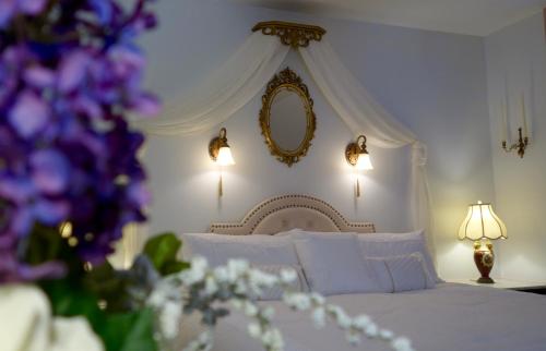 a bedroom with a white bed with a mirror and purple flowers at Acadia Bay Inn in Sullivan