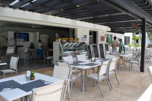 a restaurant with white tables and chairs and a kitchen at Aligio Beachfront Paradise in Las Terrenas