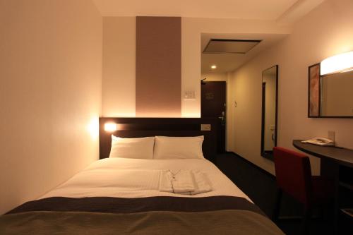 a bedroom with a white bed with a desk at Urban Hotel Kyoto in Kyoto