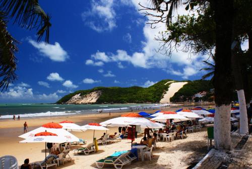 a beach with umbrellas and people sitting on the sand at Oxente Travel Apart Hotel in Natal