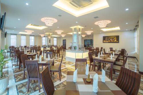 a dining room with tables and chairs and chandeliers at Phnom Penh Katari Hotel in Phnom Penh