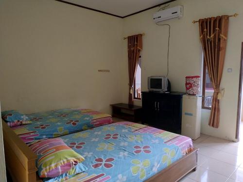 um pequeno quarto com uma cama e um frigorífico em Hotel Putra Sindang Asih em Batukaras