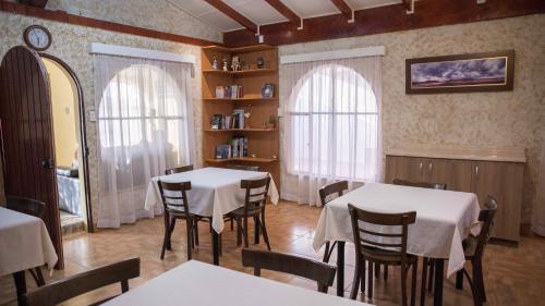a dining room with two tables and chairs and two windows at Hostal Solor in San Pedro de Atacama