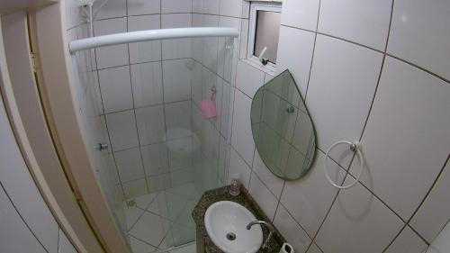 a bathroom with a sink and a shower with a mirror at Apartamento Guaratuba in Guaratuba