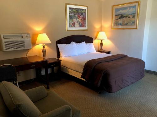a hotel room with a bed and a desk and a chair at Rodeway Inn Hermiston - Umatilla in Hermiston