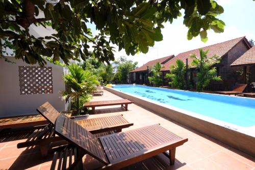 a swimming pool with wooden benches next to a building at MAY Bungalow in Mui Ne